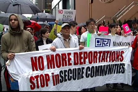 Protesters with sign reading "No more deportations, stop insecure communities"